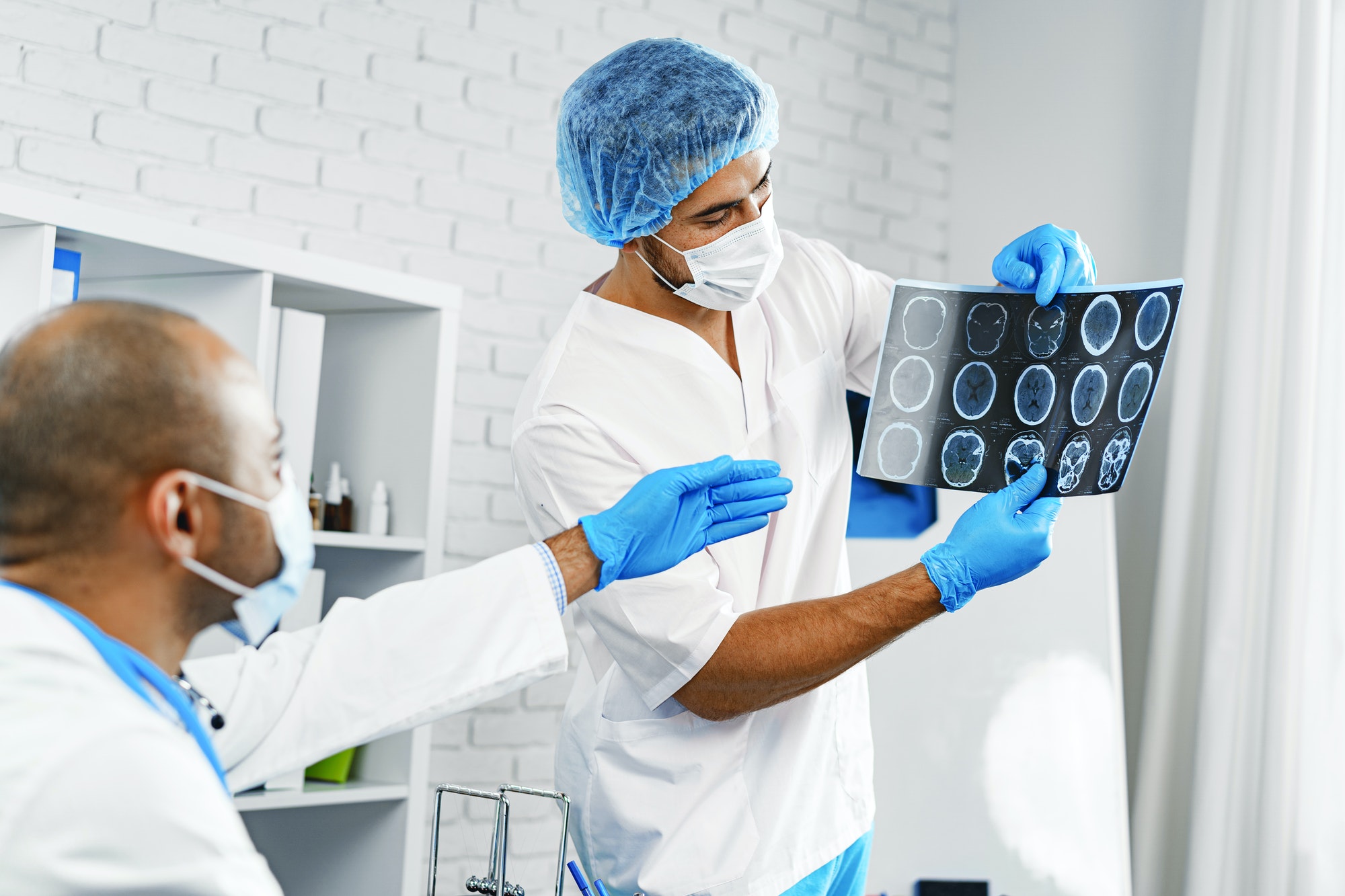 Two male doctors examine MRI brain scan of a patient in cabinet