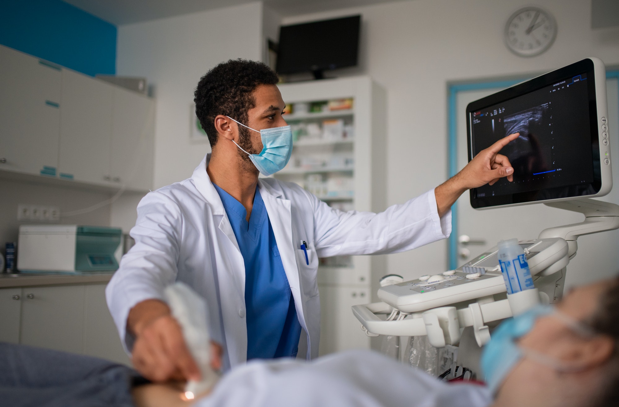 TELE-ICU - Young doctor is examining patient by using an ultrasound equipment in clinic