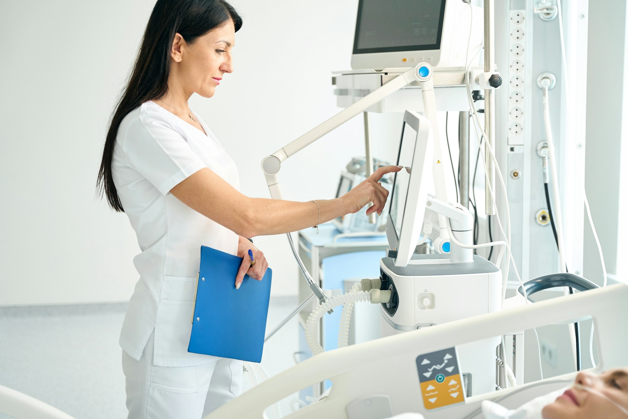 Nurse adjusts the settings of monitoring equipment
