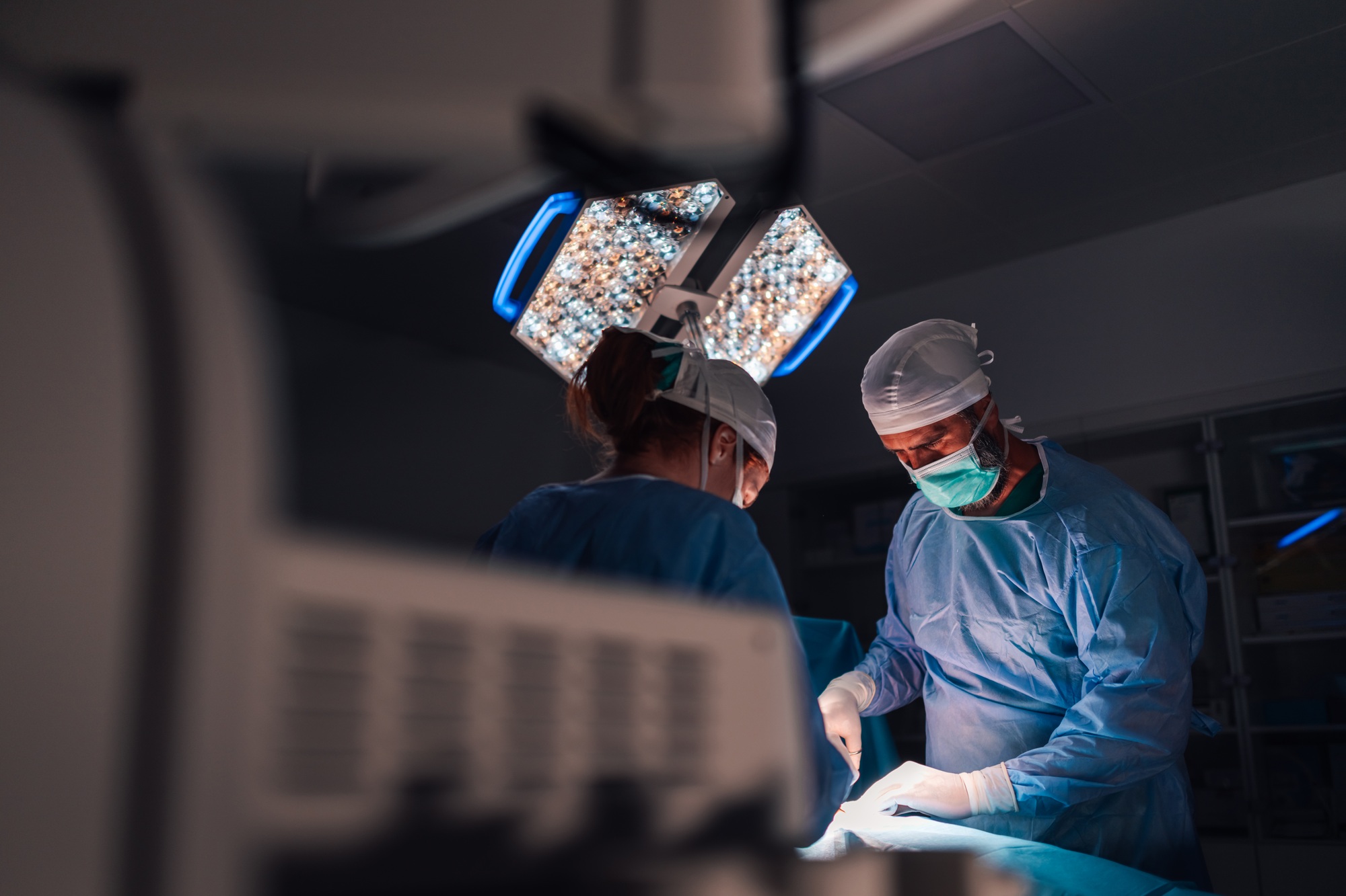 Surgeons in blue gowns performing a critical operation together.